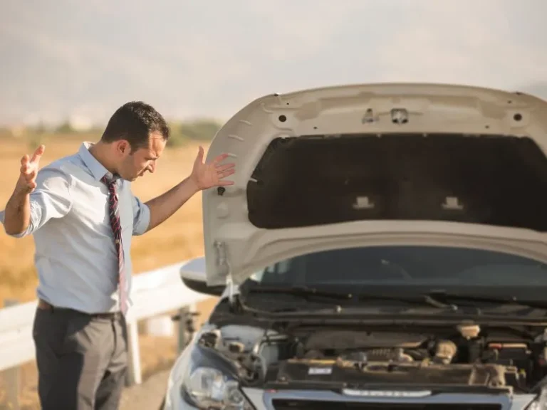 A driver stood at the roadside beside a broken-down car with the bonnet open